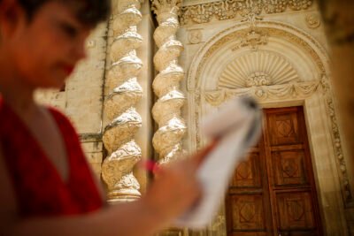 Donatella che scrive su carta con lo sfondo di una bellissima chiesa con colonne tortili