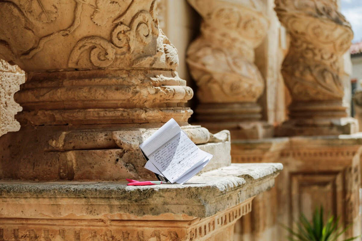 Un block notes e una penna sulla base della colonna tortile di una chiesa barocca di Palazzolo Acreide