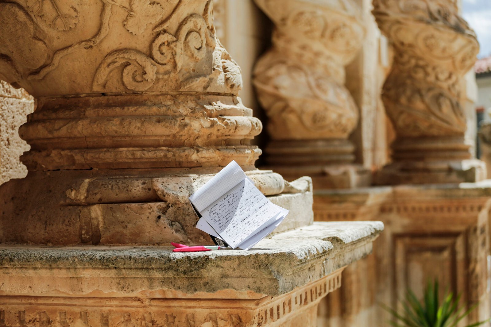 Un block notes e una penna sulla base della colonna tortile di una chiesa barocca di Palazzolo Acreide